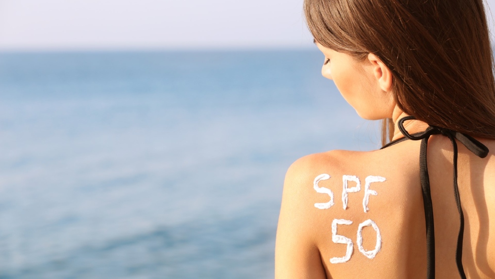 Ragazza applica la crema solare per proteggere la pelle durante l’estate