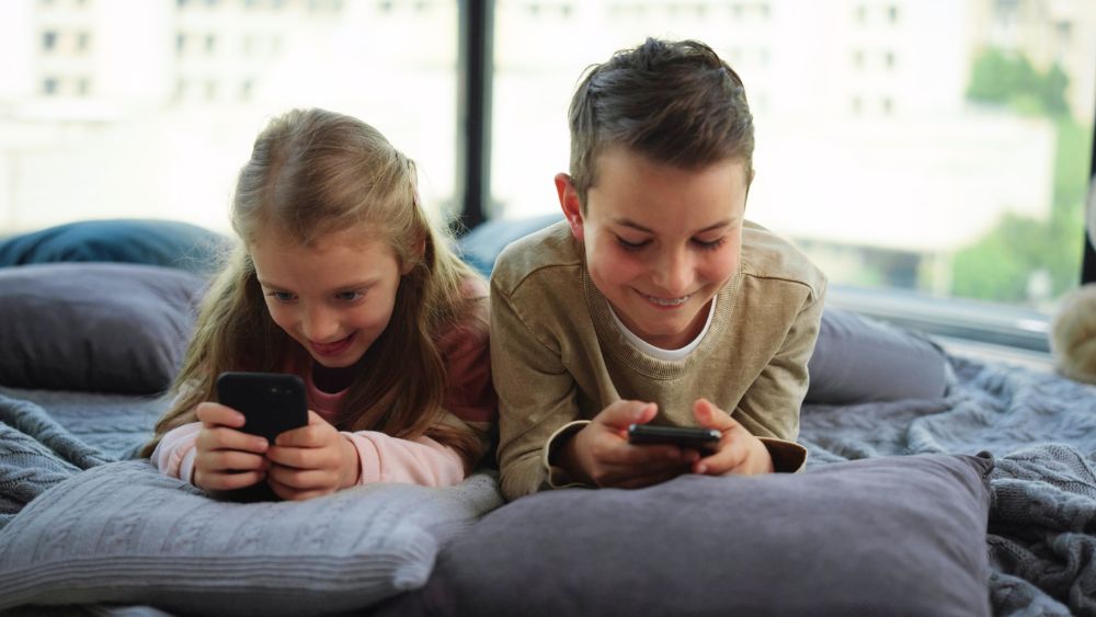 Due bambini che giocano con lo smartphone - Screen time dei bambini italiani