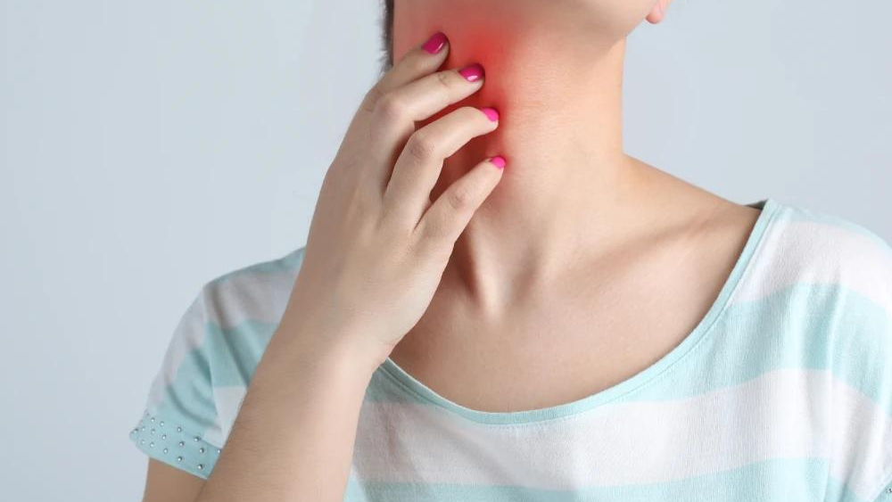 Una donna si tocca il collo arrossato dovuto a un intolleranza alimentare