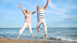 Una donna e un uomo che ahnno intrapreso un programma longevity,saltano su una spiaggia