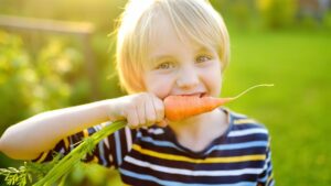 Un bambino che mangia auna carota - 7 consigli per rinforzare il sistema immunitario tutto l’anno 
