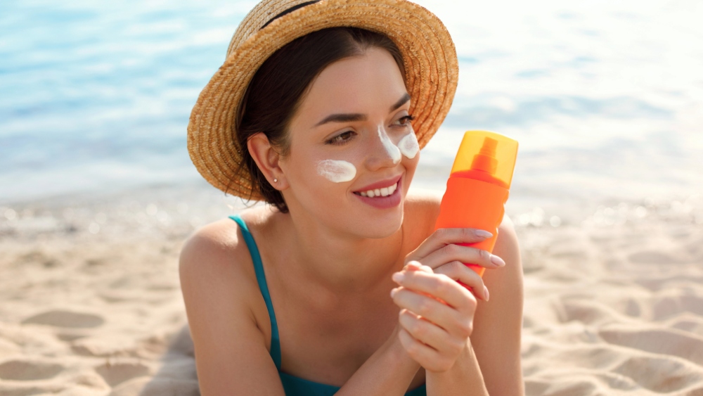 ragazza in spiaggia con un cappello di paglia e un gelato in mano - Noi e il sole: amici per la pelle