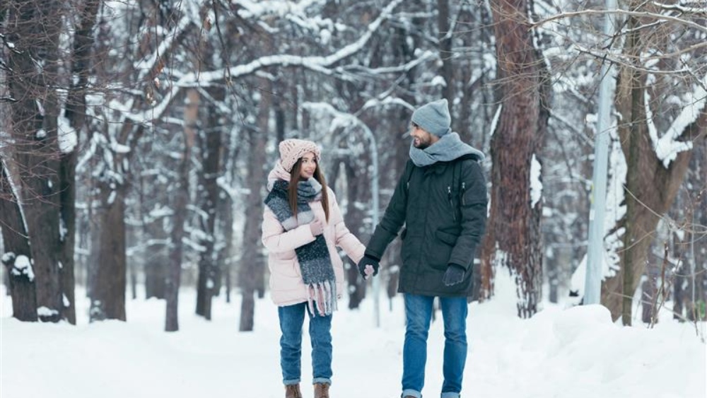 Perché uscire al freddo fa bene alla salute - coppia di ragazzi in un bosco sotto la neve invernale