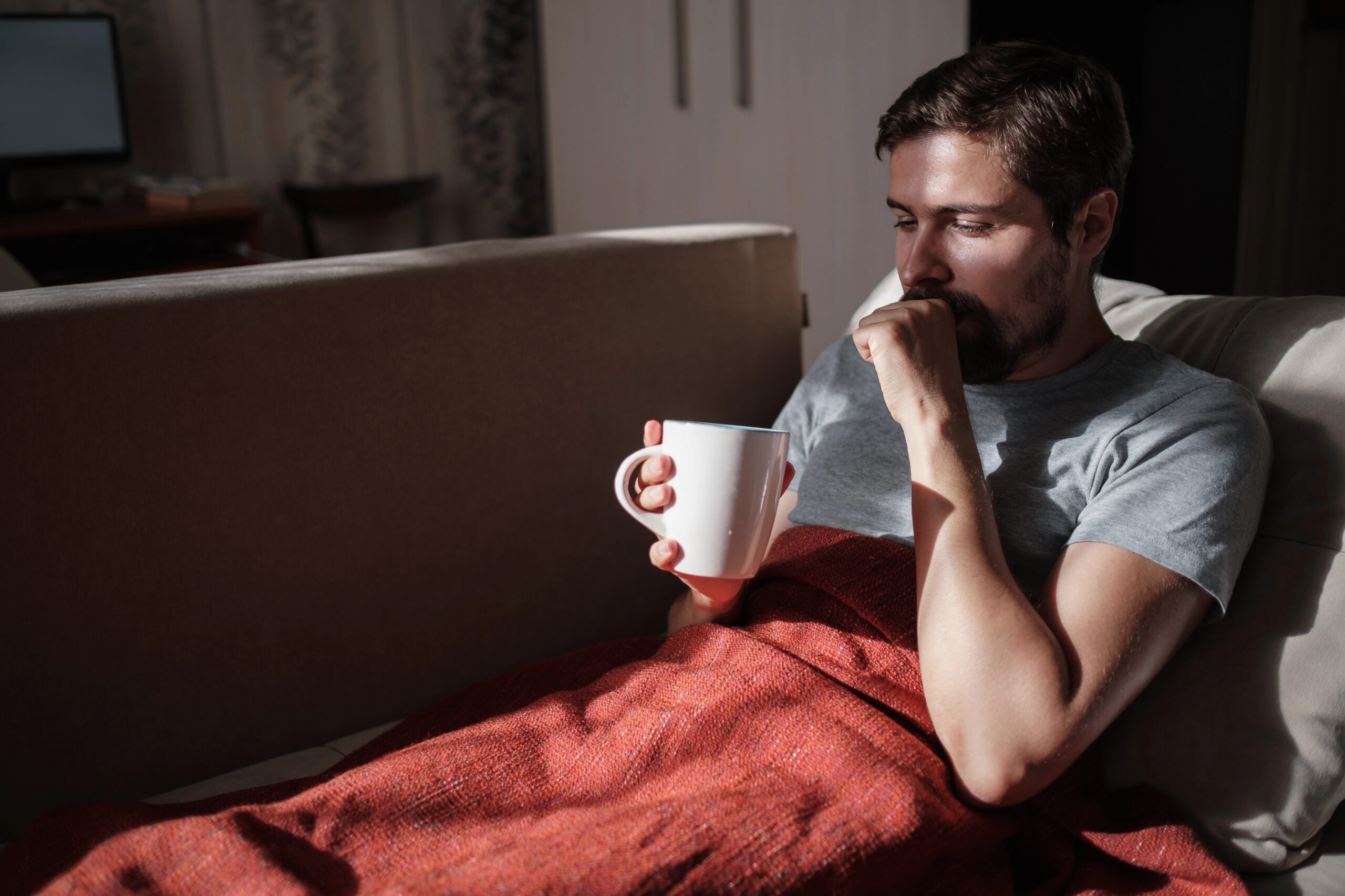 Giovane malato post influenza che beve una tisana